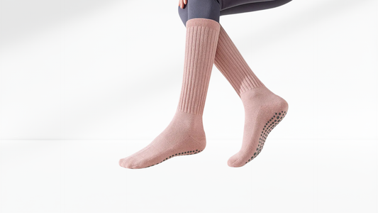 Pink socks with grip sole worn by a person on a white background