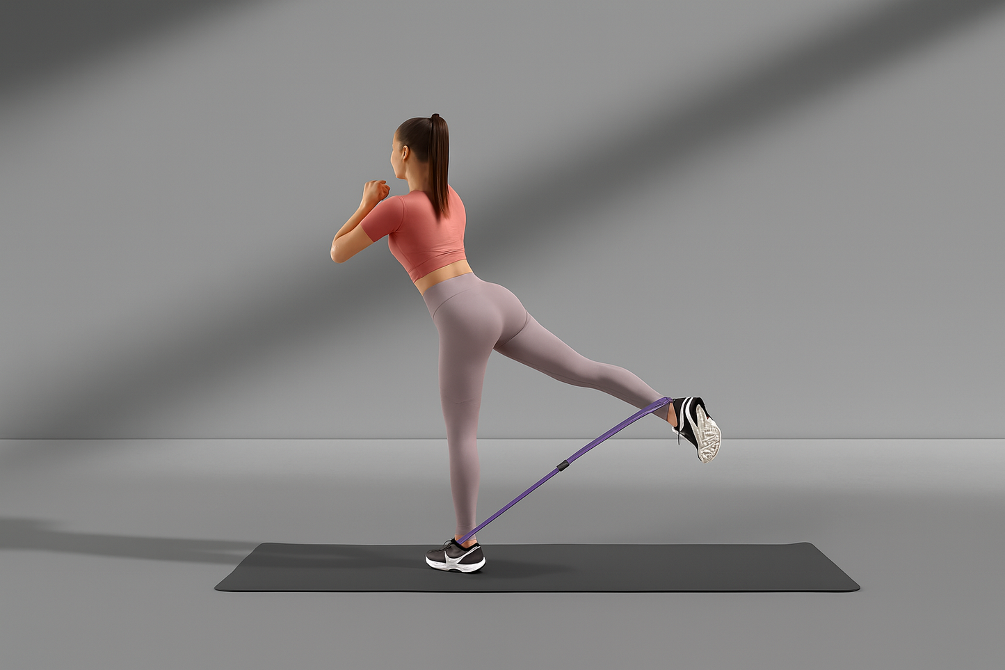 Woman exercising with a purple resistance band on a gray background