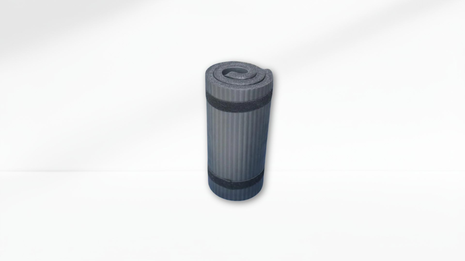 A rolled black yoga mat secured with two black straps, displayed upright on a white background.
