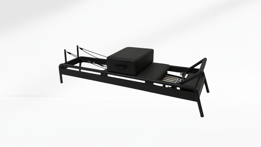Black Pilates Reformer with a box on a white background