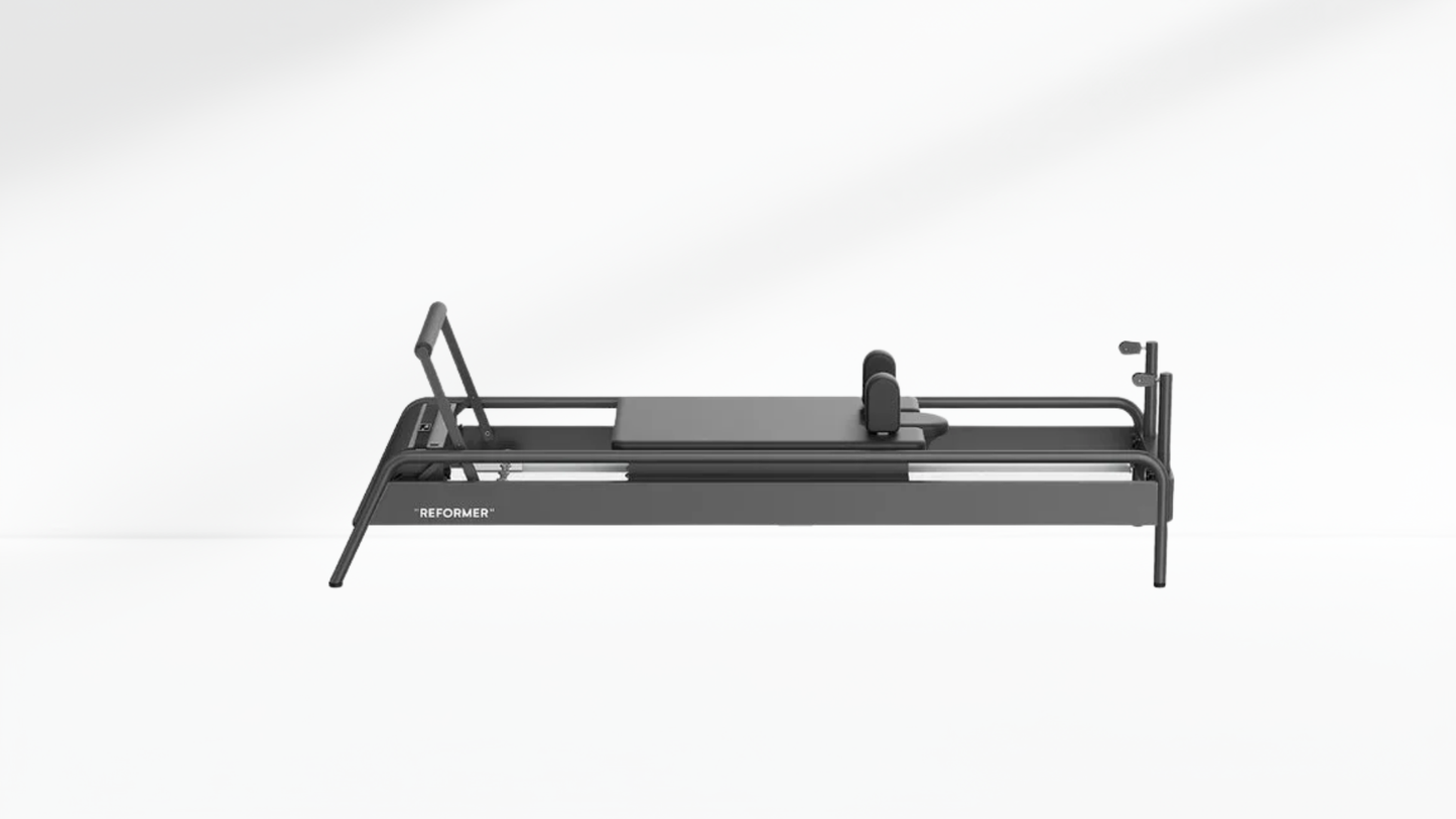 Black Pilates reformer on a white-grey background