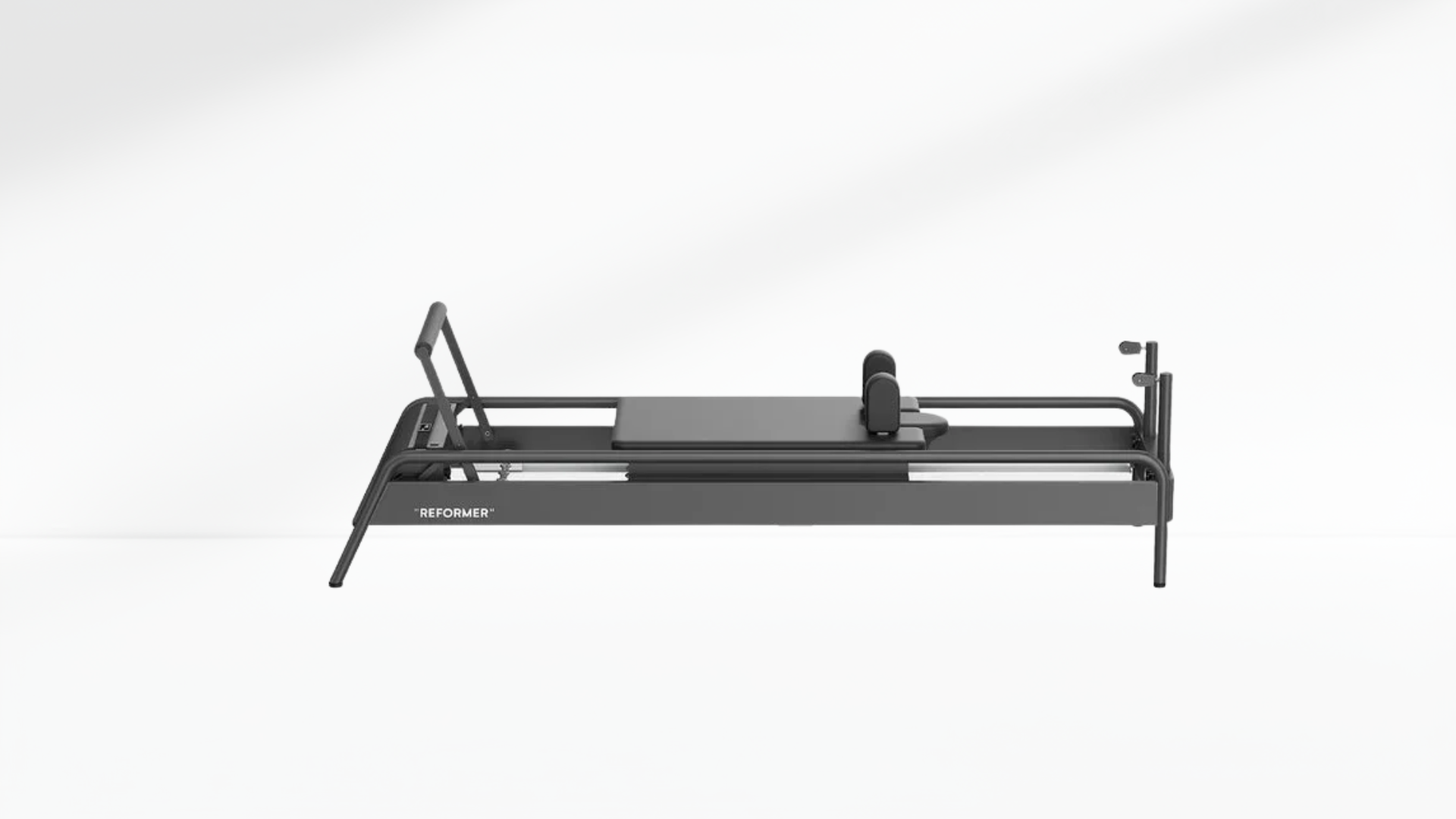 Black Pilates reformer on a white-grey background