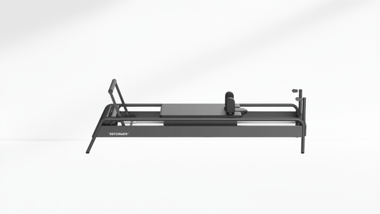 Black Pilates reformer on a white-grey background