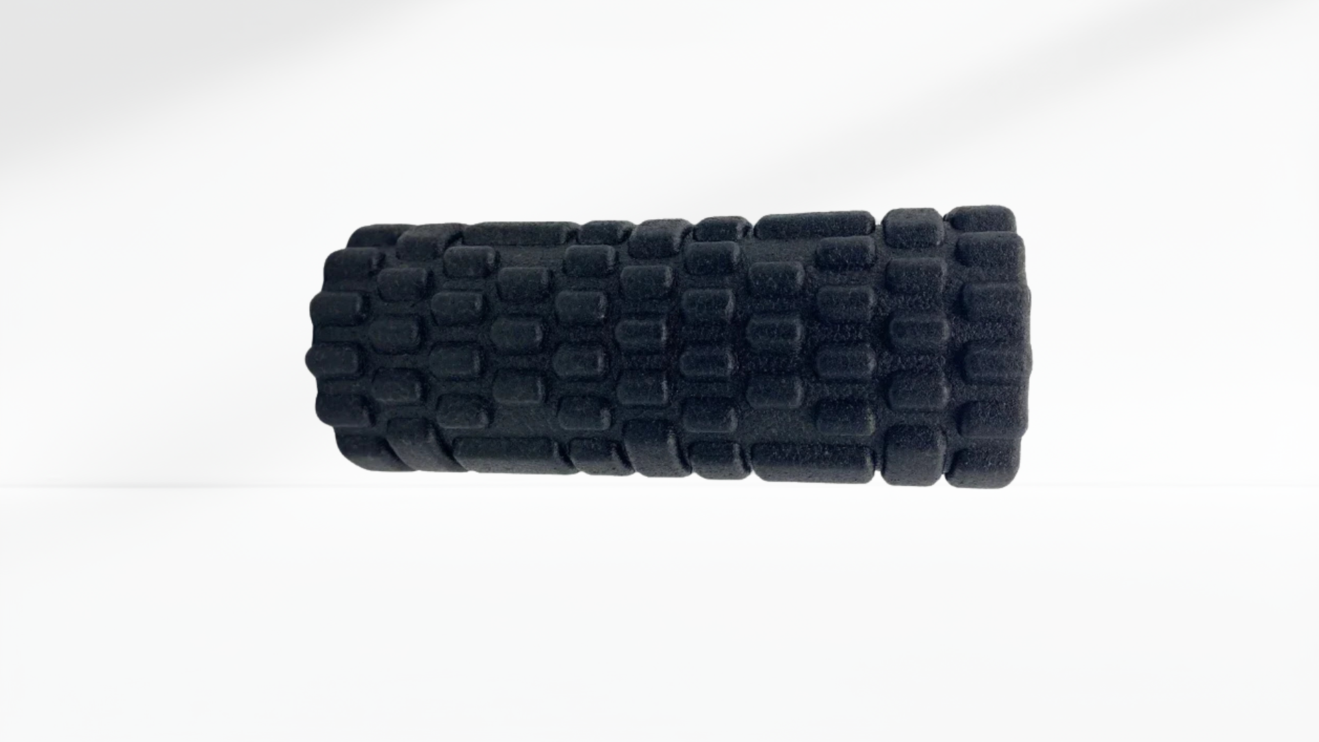 Black foam roller with textured surface on a white background