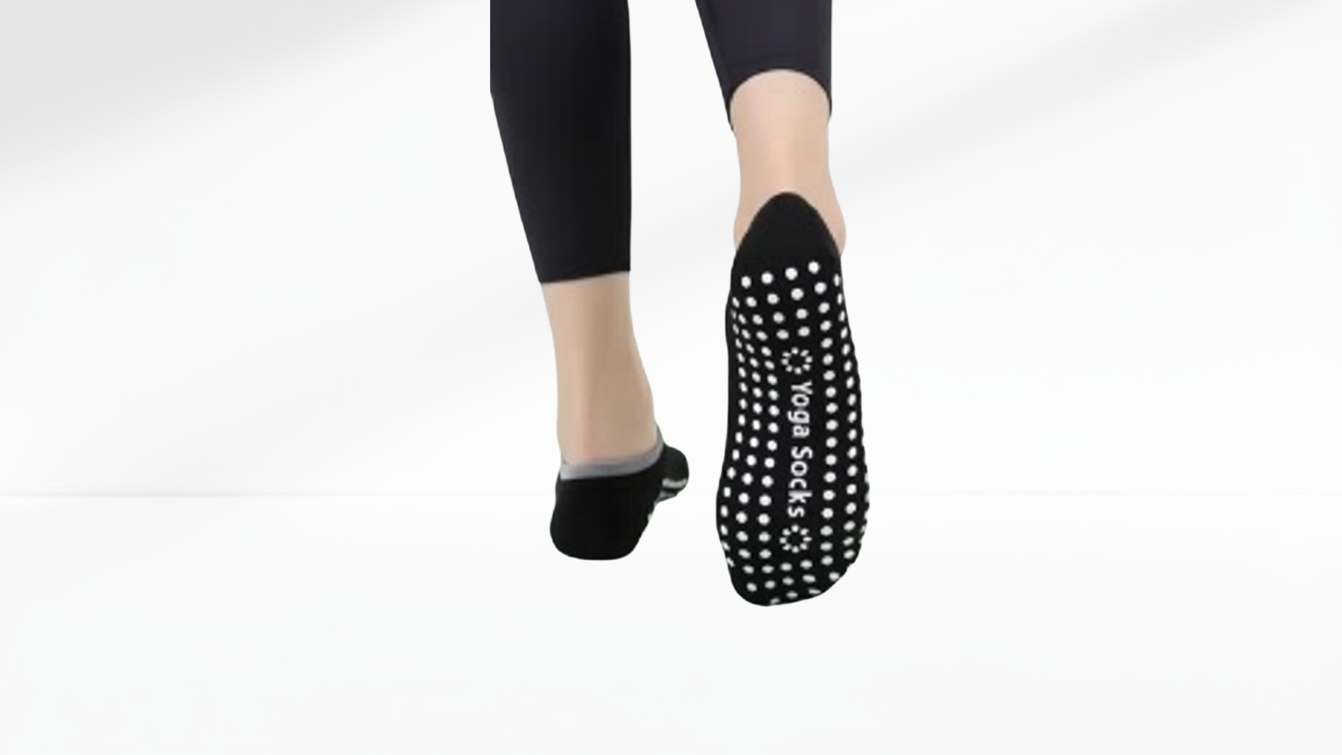 Black grip socks ballet worn with black leggings on a white background