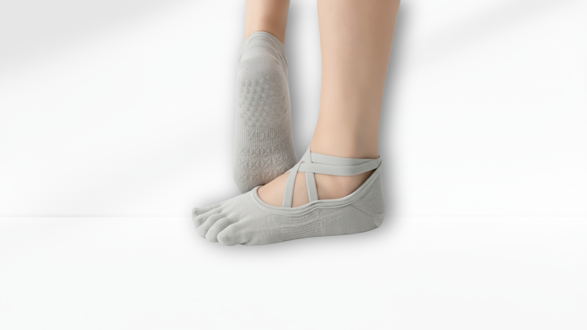 Gray toe-separated socks worn with bare feet on a light gray background