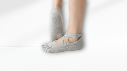 Gray toe-separated socks worn with bare feet on a light gray background