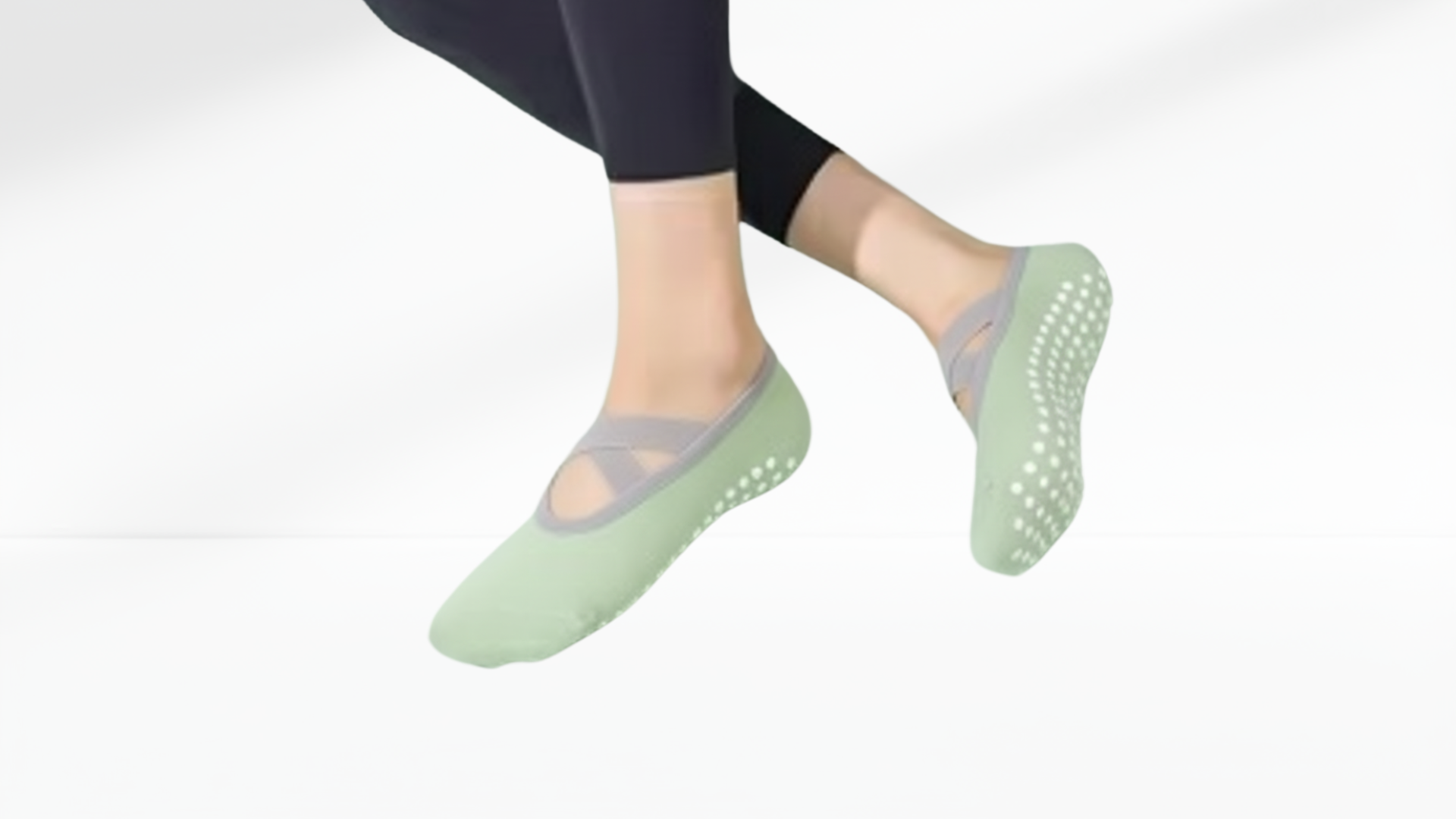 Green non-slip grip socks ballet worn with dark leggings on a white background