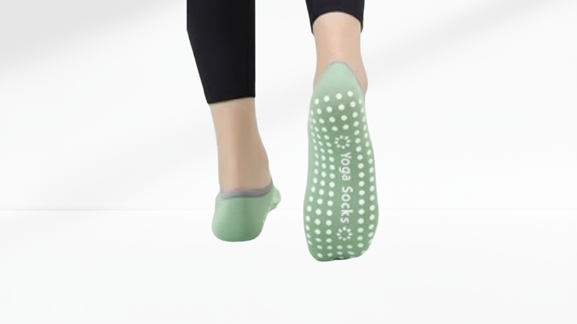 Green yoga grip socks ballet with textured sole worn by a person on a white background