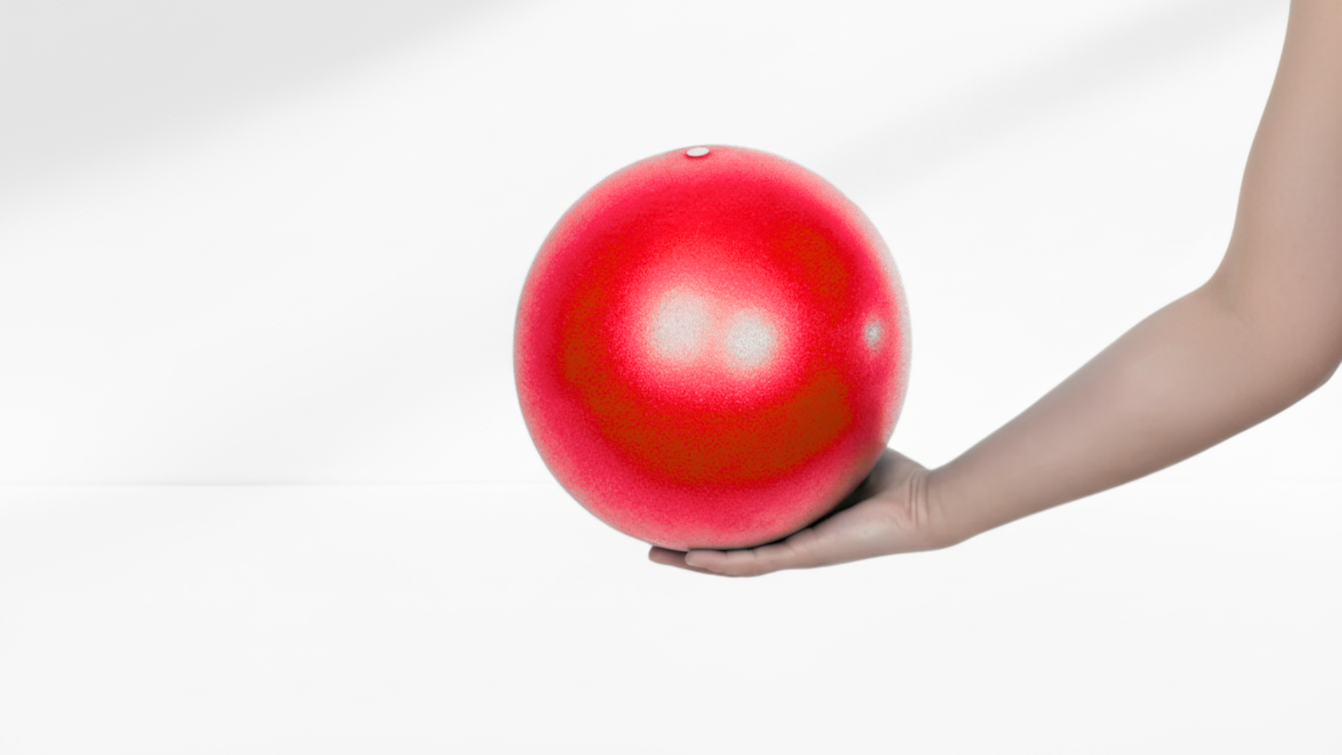 Hand holding a red ball against a white background
