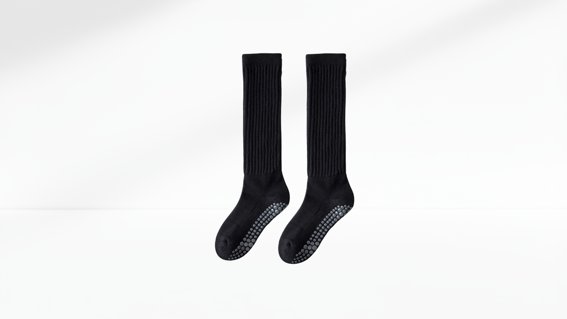 Pair of black socks with non-slip dots on a white background