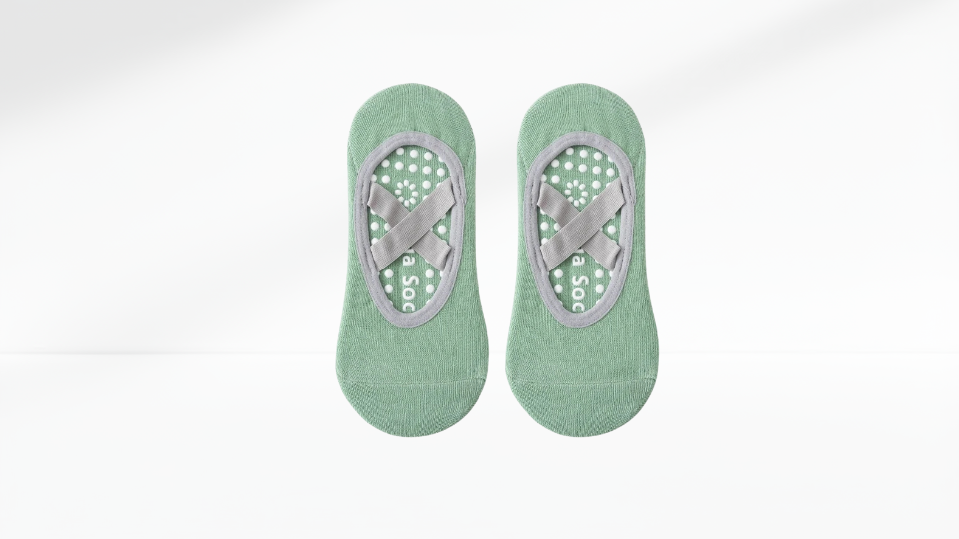 Pair of green grip socks ballet with gray sole design on a white background