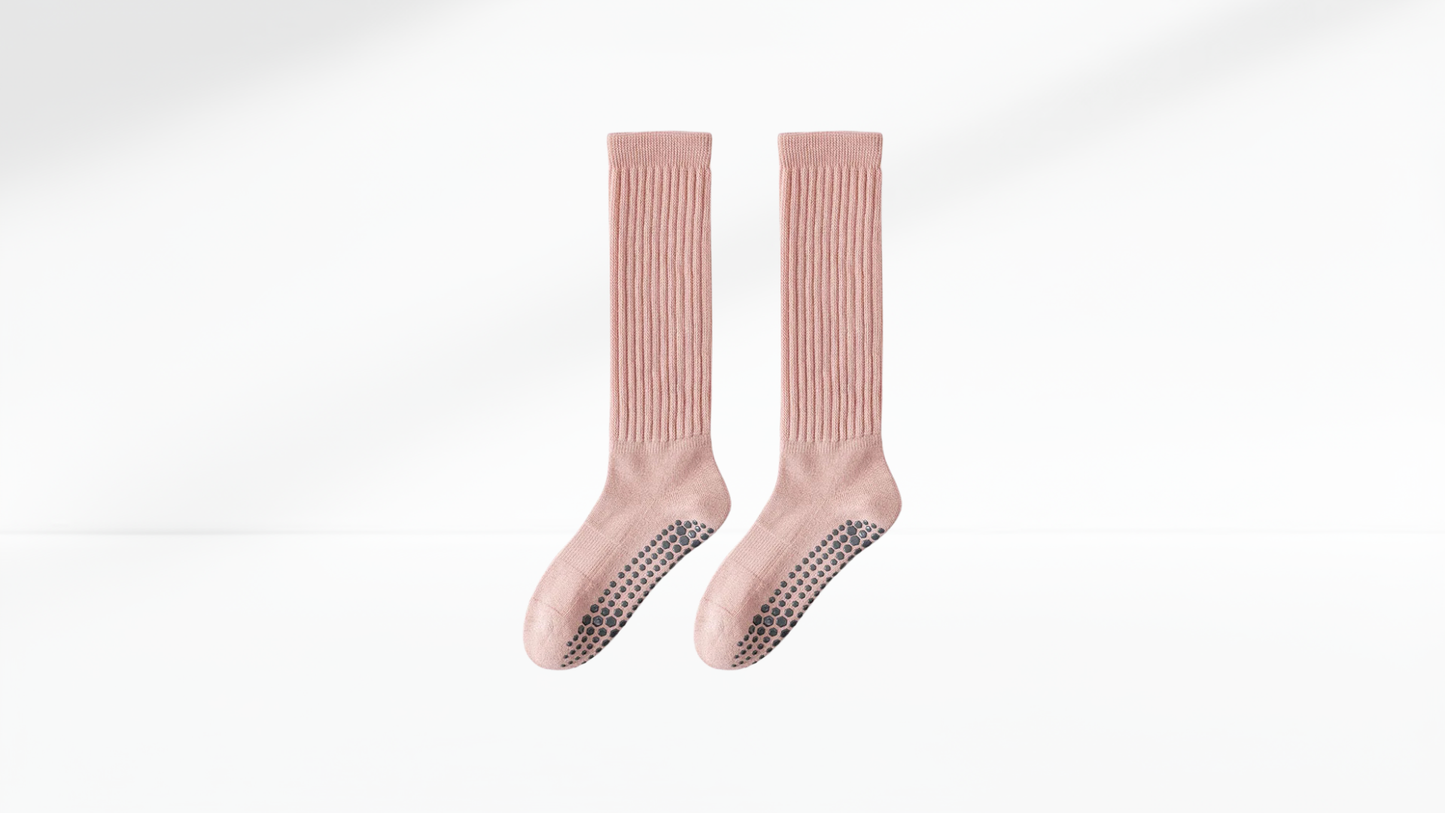 Pair of pink knee-high grip socks with textured sole on a white background