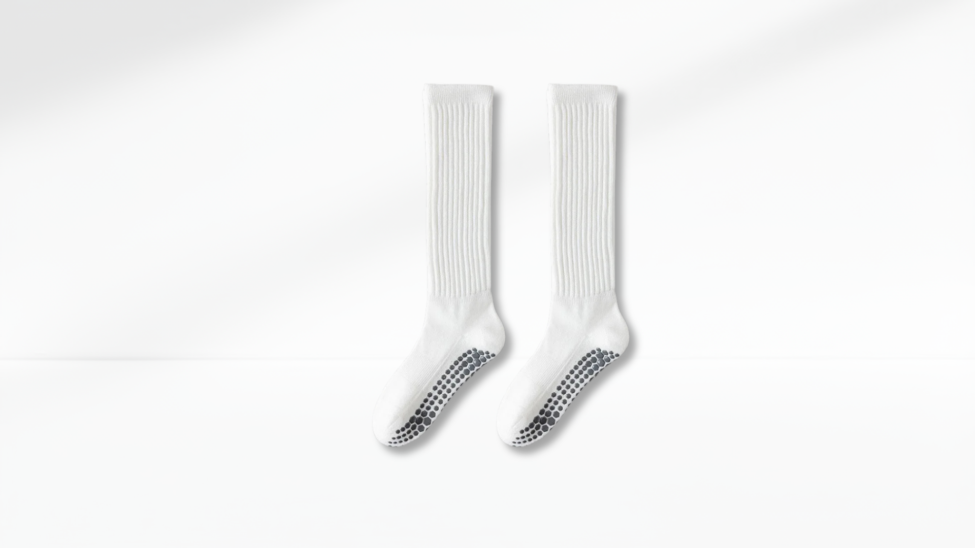Pair of white grip socks with black accents on a white background