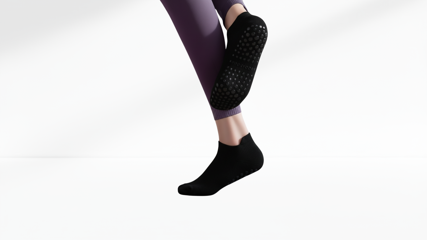 Person wearing black textured grip socks and purple leggings on a white background