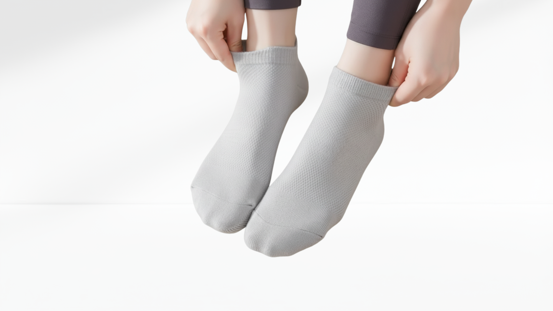 Person wearing gray grip socks on a white-grey background