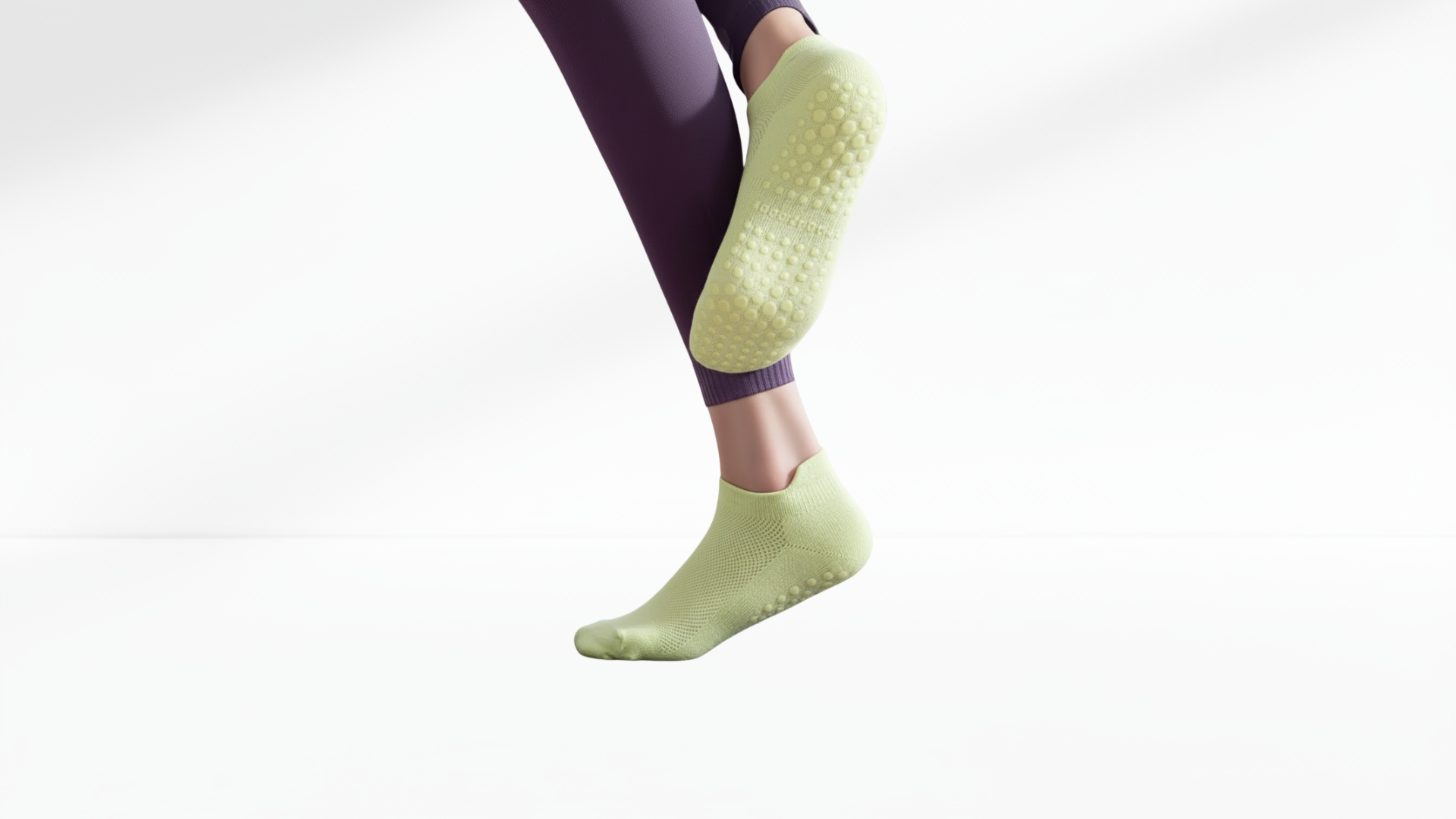 Person wearing green grip socks with a white background