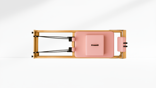 Pink and wooden pilates reformer on a white background