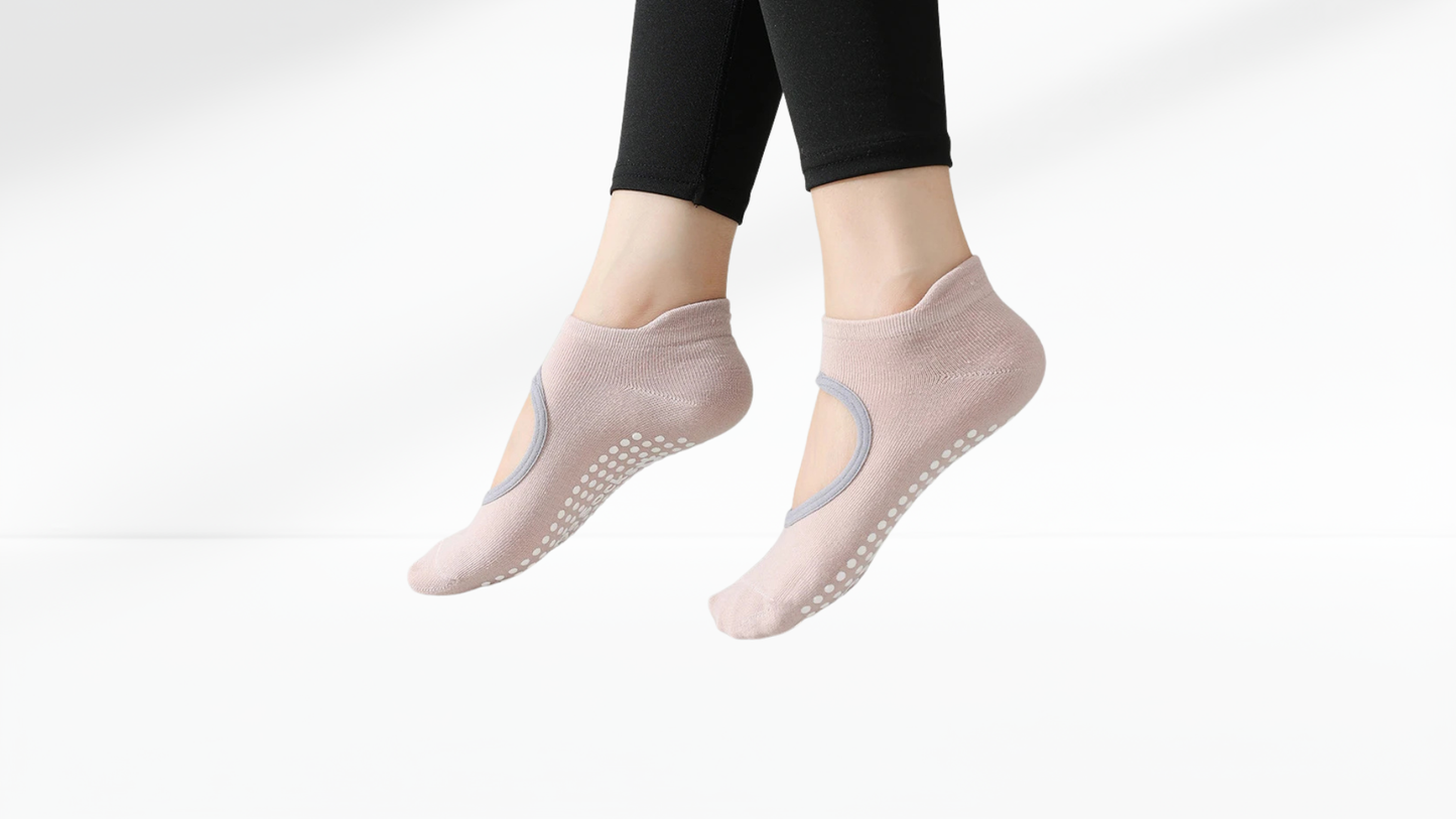 Pink yoga grip socks with grip dots worn by a person on a white background.