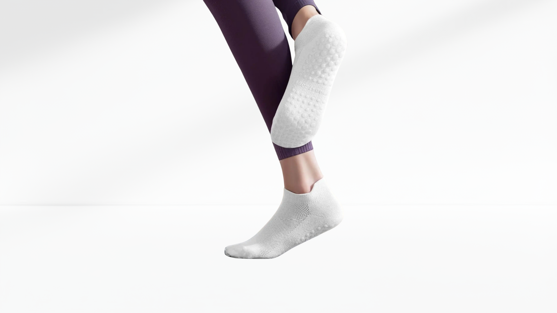 White grip socks worn with purple leggings on a light gray background