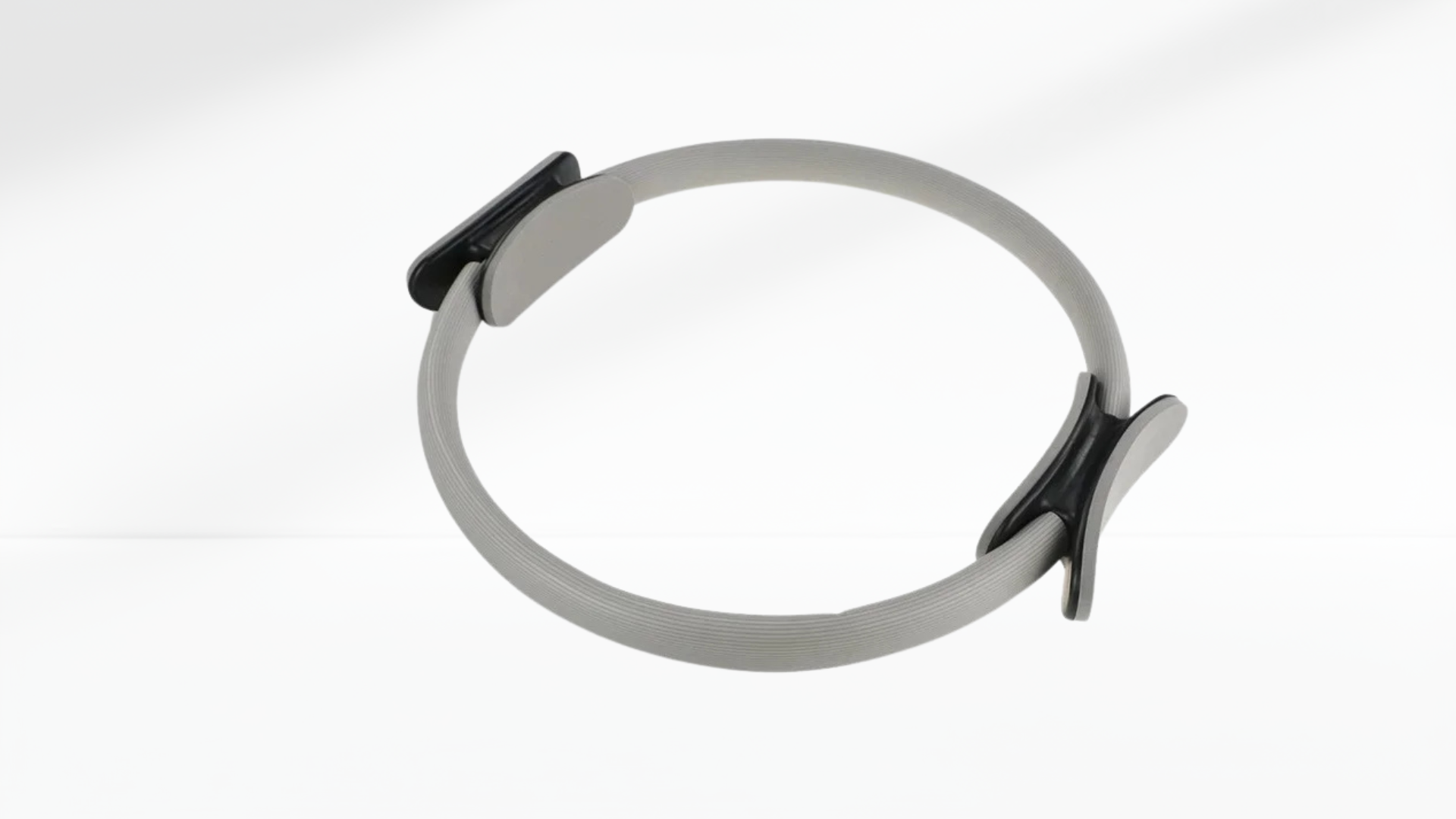grey pilates ring with a black clip on a white background