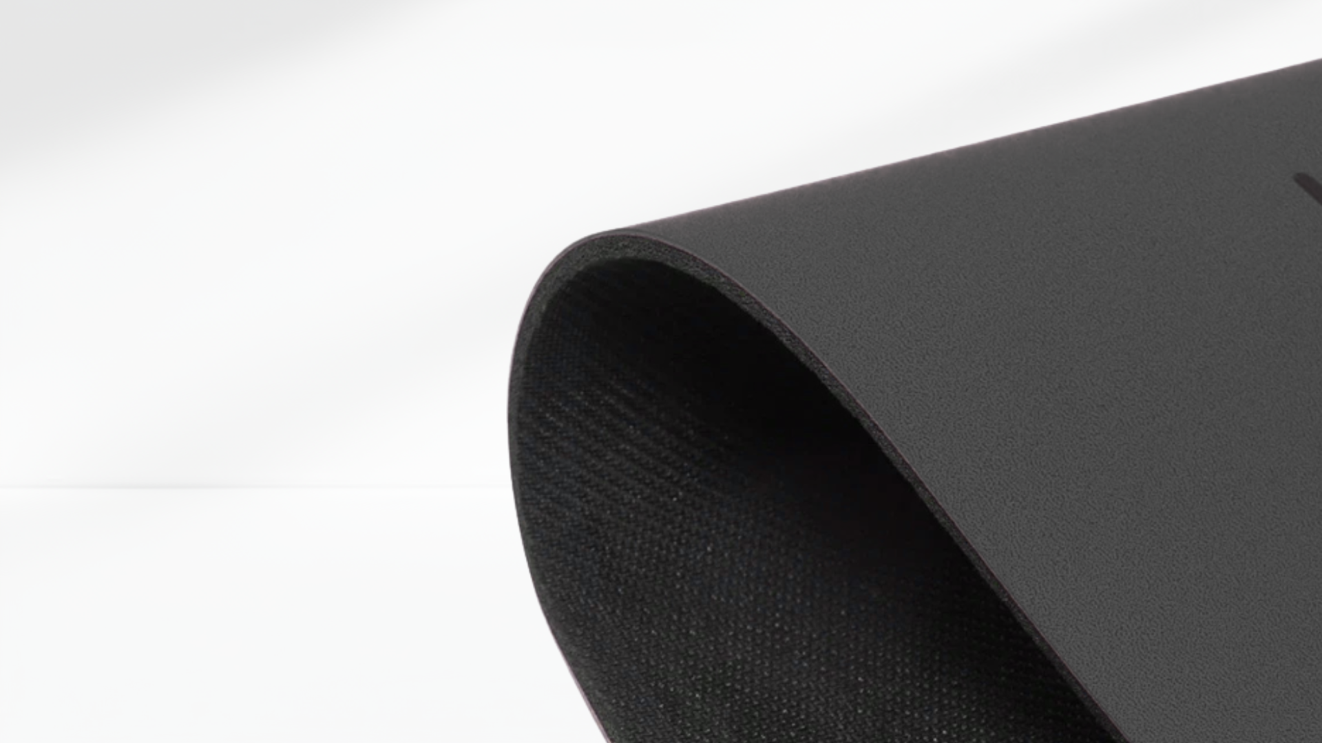 Close-up side view of a black yoga support mat showing its curved edge and textured anti-slip surface.